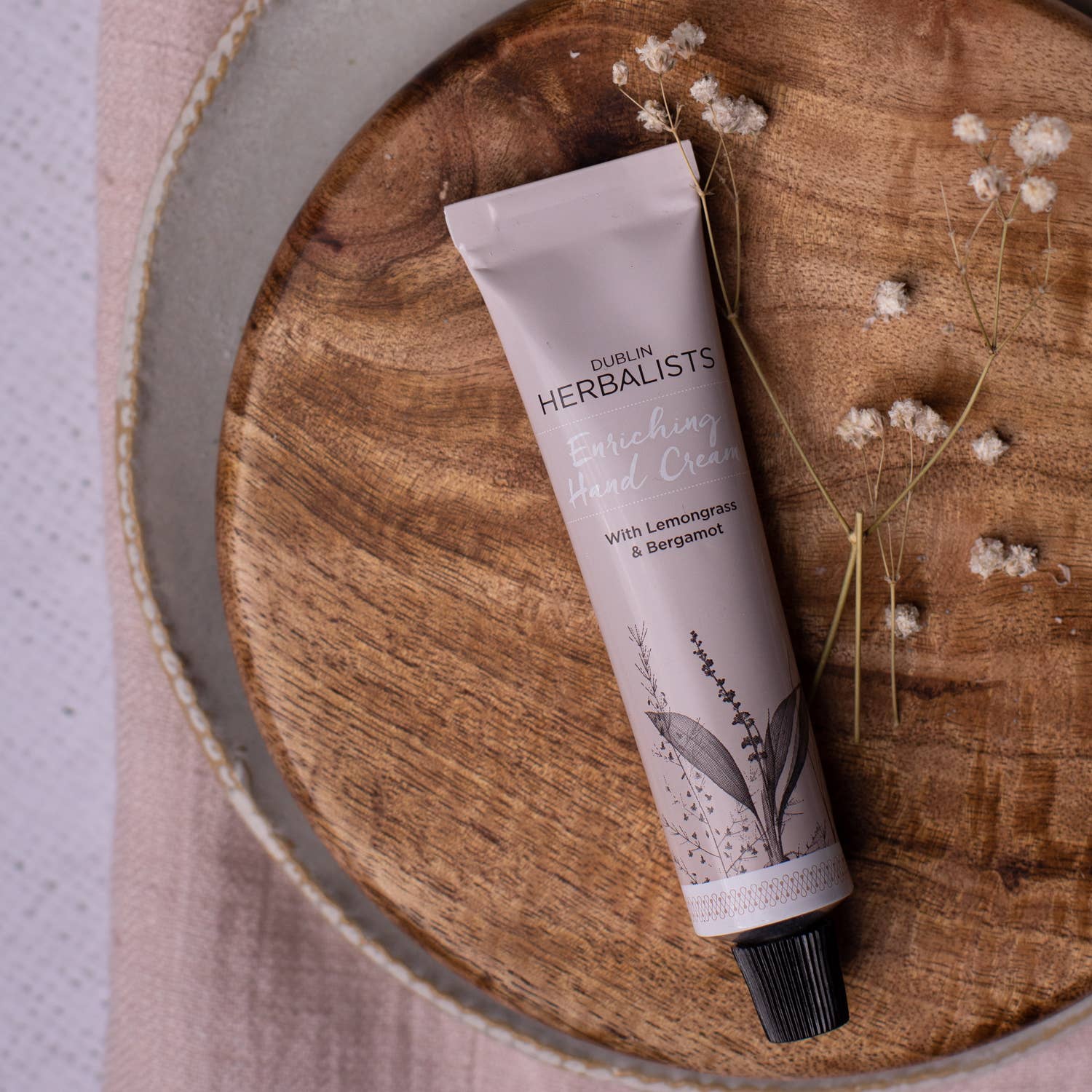 Dublin Herbalists Lemongrass and Bergamot Hand Cream 30ml - tube lying on a wooden board with dried flowers